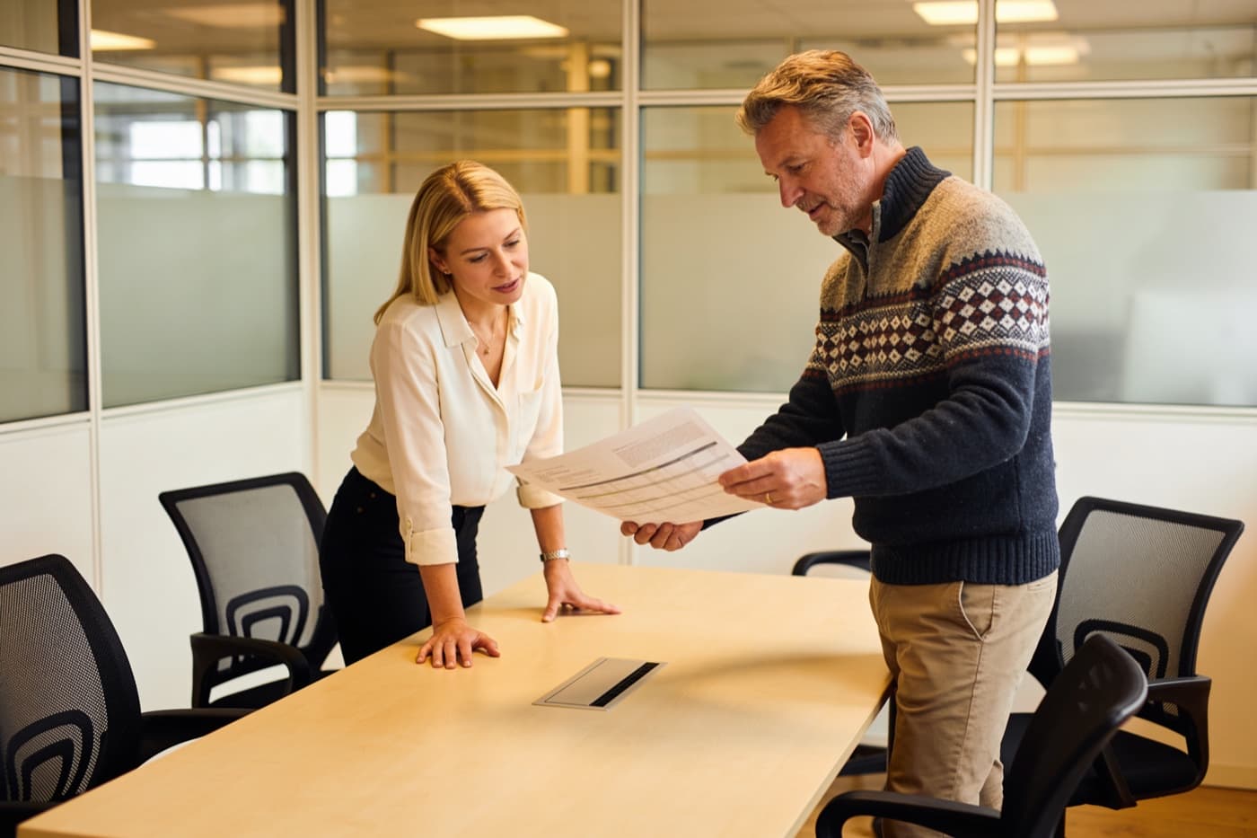 Zwei Kolleginnen und Kollegen einer Recruiting-Agentur besprechen ein ausgedrucktes Dokument
