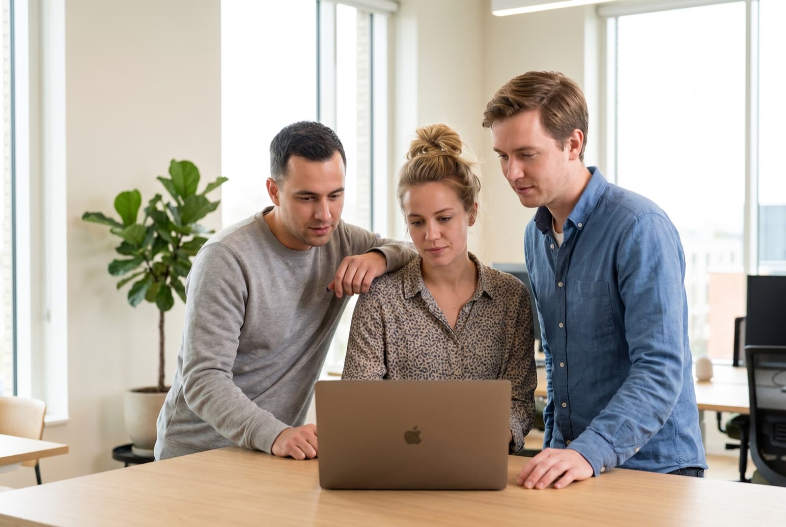 Ein kleines Agentur-Team arbeitet gemeinsam an einem Laptop