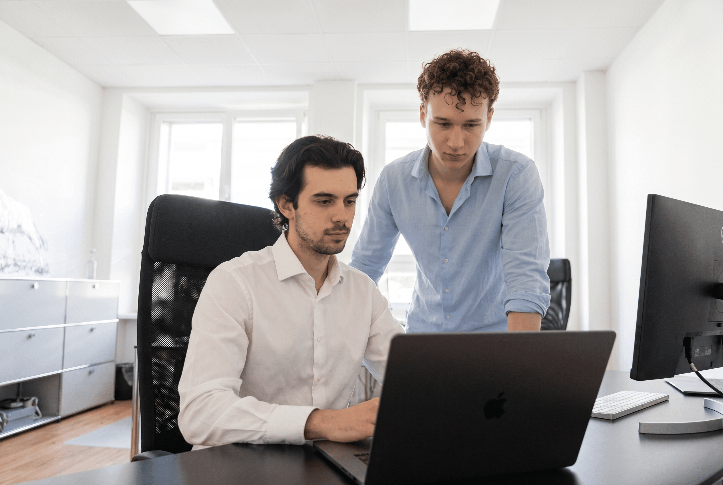 Zwei junge Kollegen arbeiten gemeinsam am Laptop im Grabosch-Büro